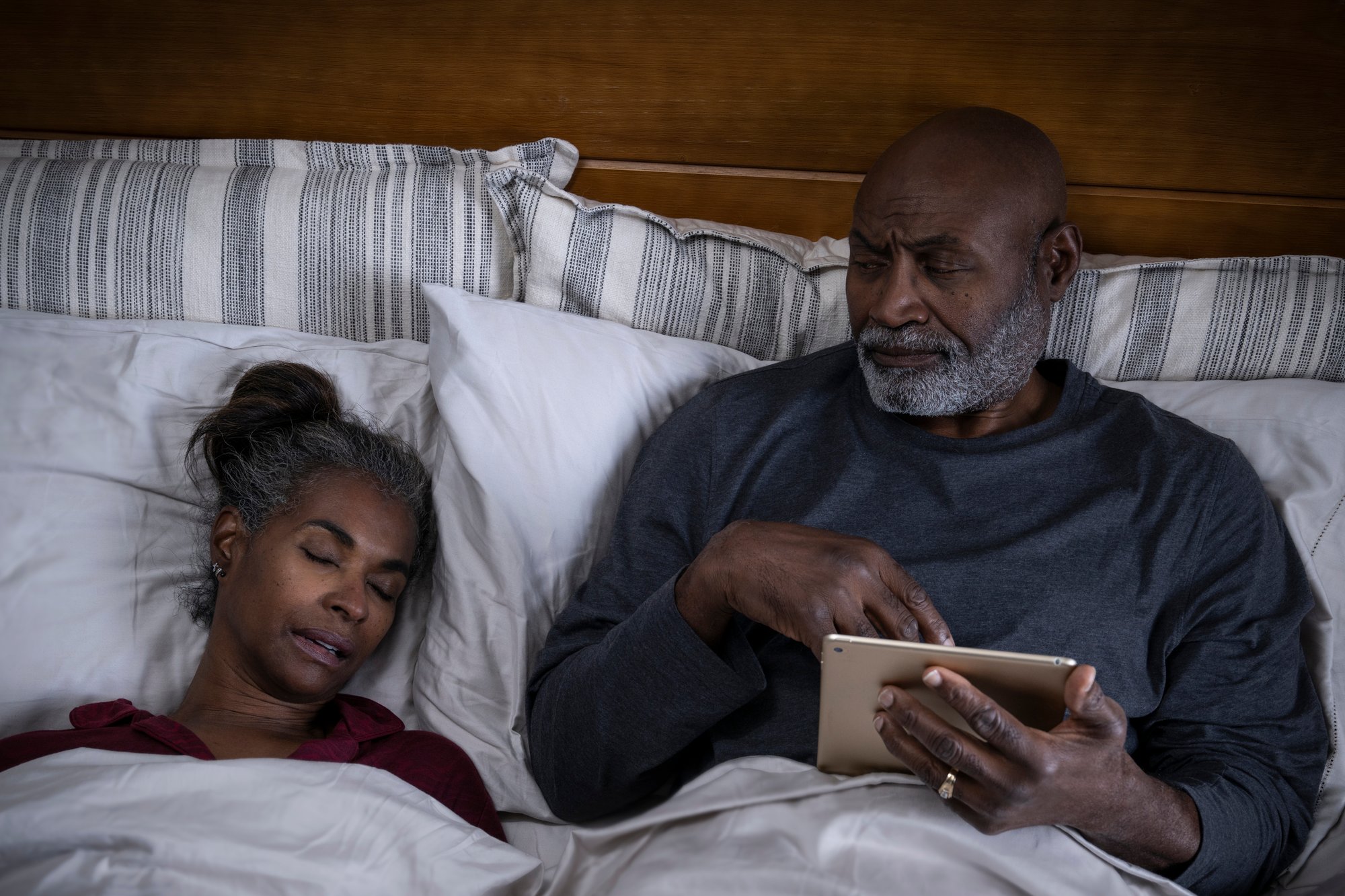 Man and woman in bed, man unable to sleep next to woman 