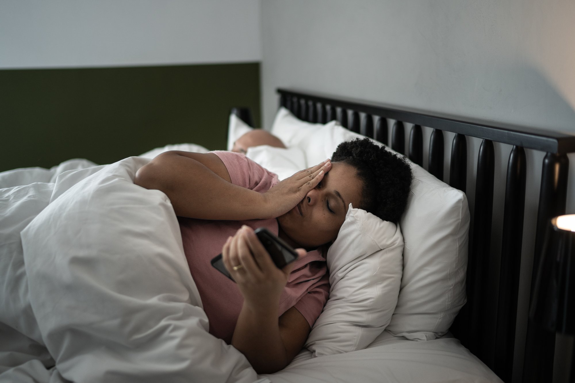 Woman laying in bed with her phone, unable to sleep