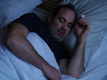 Man sleeping, on his finger he has a sleep test sensor on.