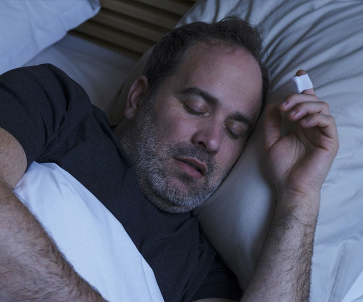 Man sleeping, on his finger he has a sleep test sensor on.