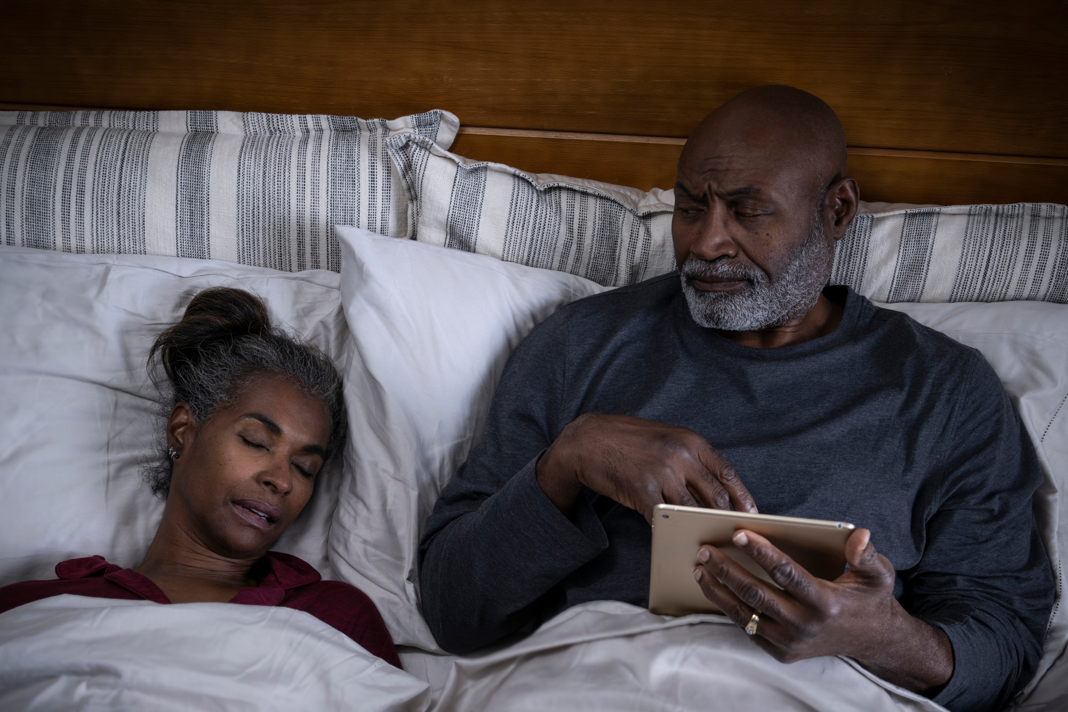 Man and woman in bed, man unable to sleep next to woman 