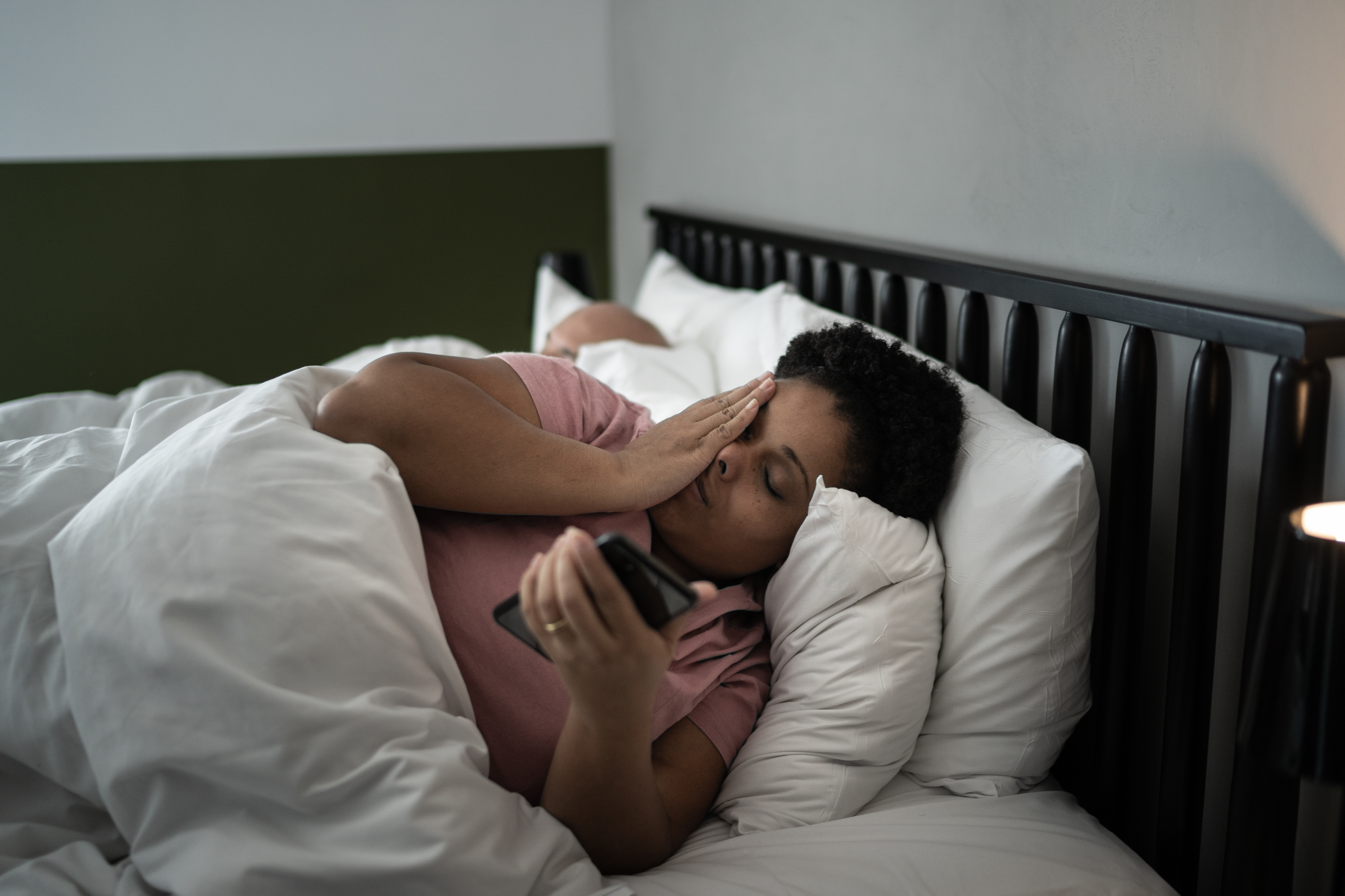 Woman laying in bed with her phone, unable to sleep