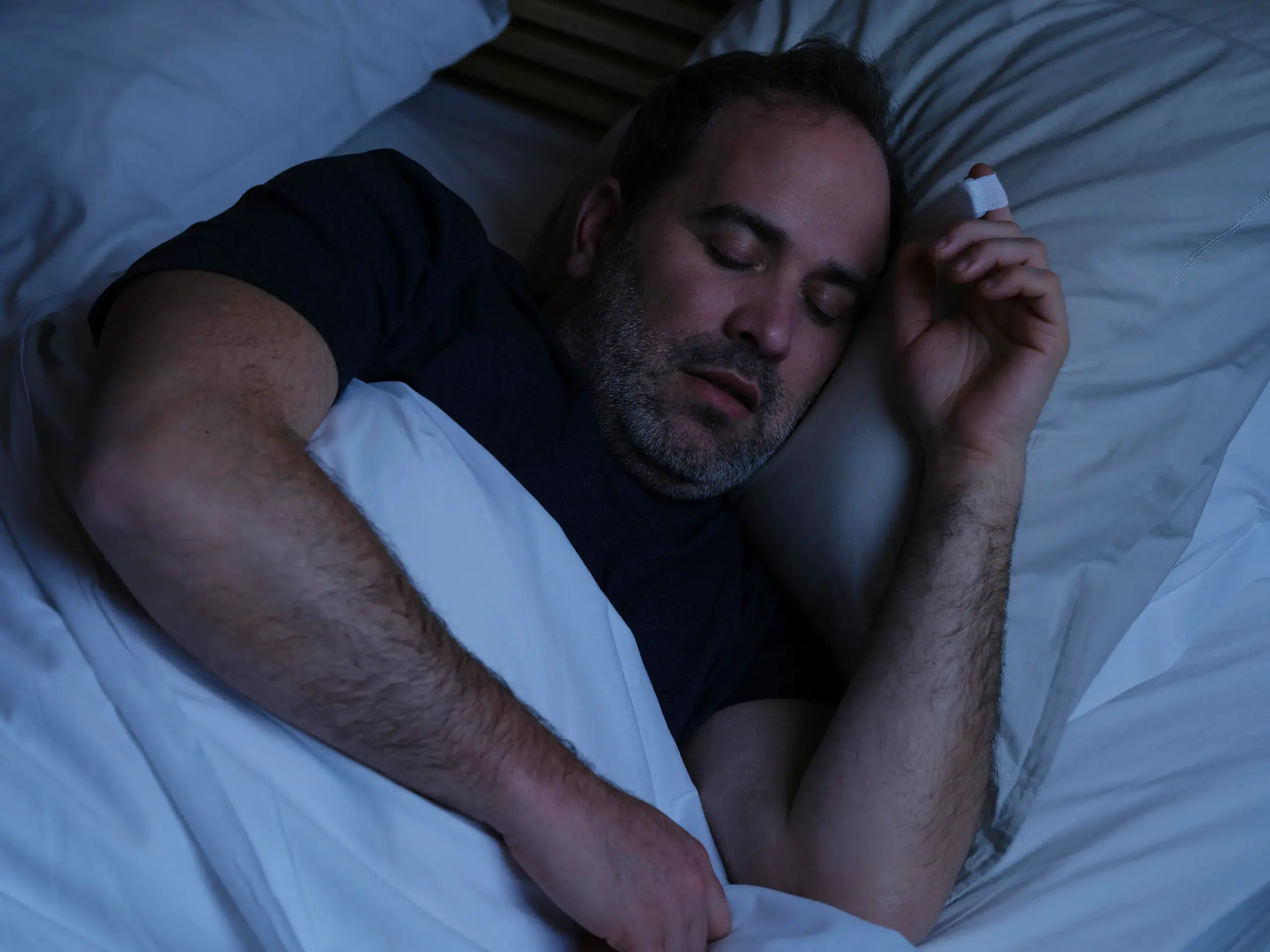 Man sleeping, on his finger he has a sleep test sensor on.